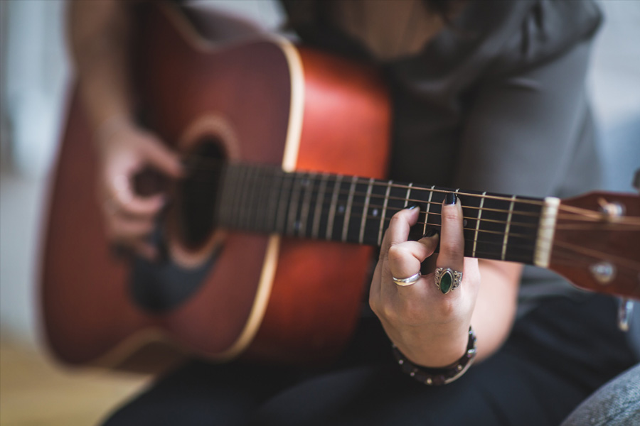 Close-up of guitar being played by female musician.