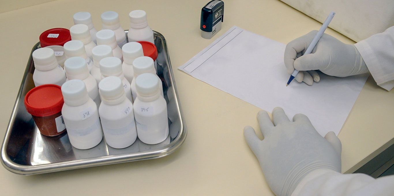 Medicine bottles on a tray next to medical researcher who is filling out a form