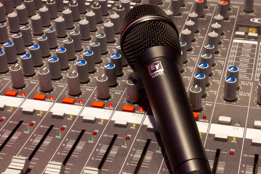 Black wireless microphone on grey and multicoloured audio mixer