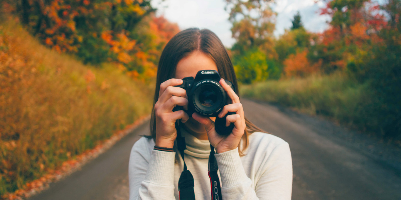 Female photographer standing in front of mountainous landscape