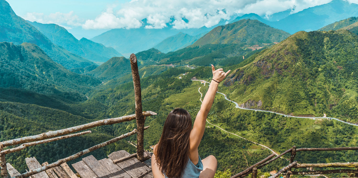 Female raising hand in joy, sitting in the mountains of northern Vietnam