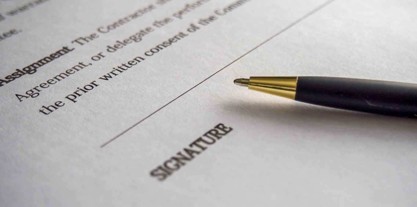 A ballpoint pen lying on top of a typed contract with a blank signature line