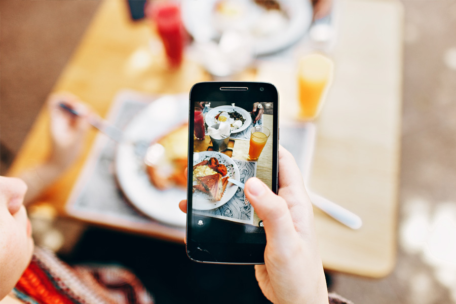 Person holding an iPhone with an image of their restaurant meal on screen