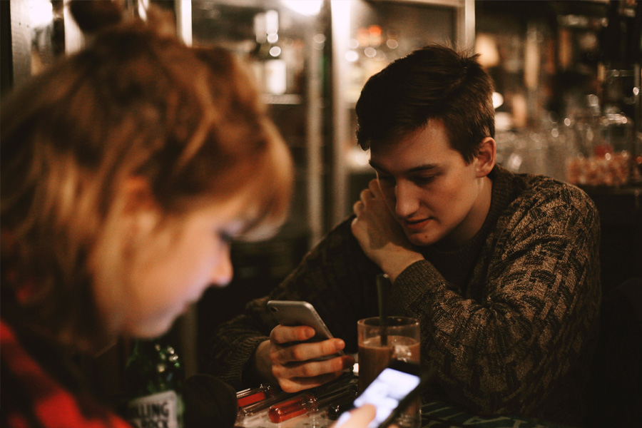 Male and female in a restaurant using an app on their smartphones