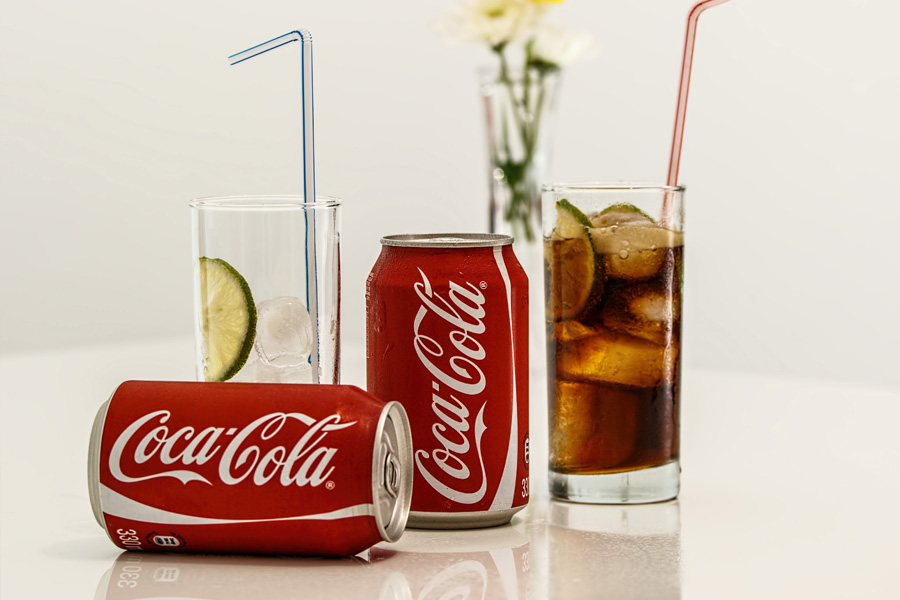 Coca-Cola cans and glasses with lime and ice.